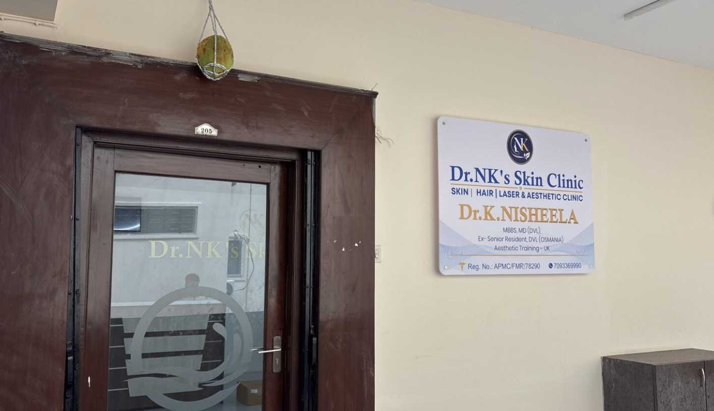Entrance and signage board at Dr. NK's Skin Clinic showing Dr. K Nisheela's name and qualifications